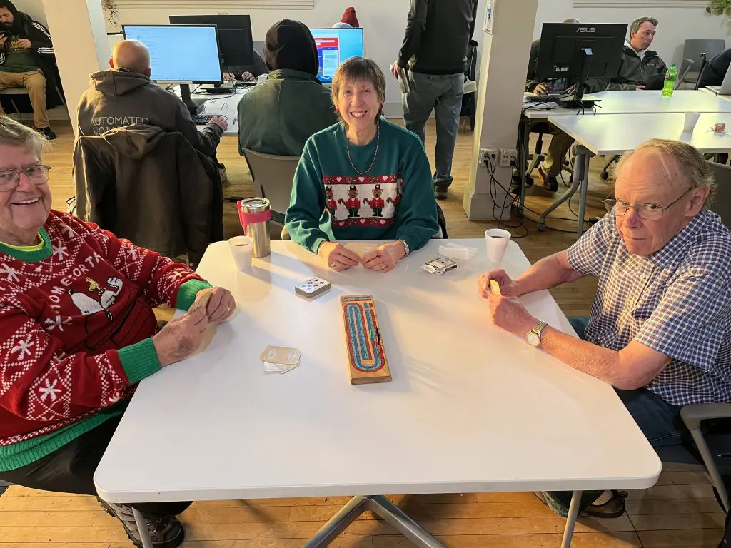 3 people sitting at a table playing Cribbage