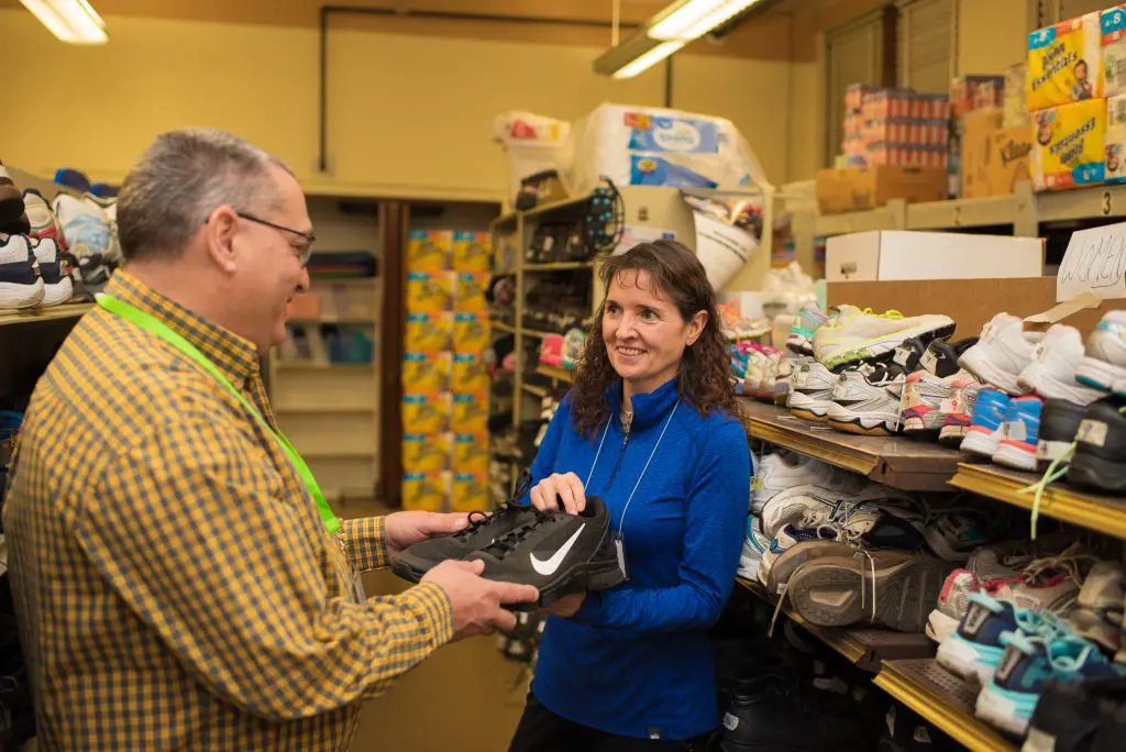A female volunteer showing another volunteer a pair of shoes