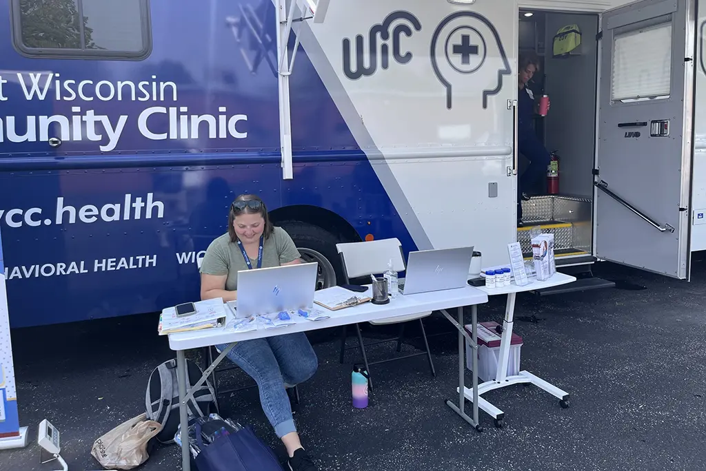 NEW Community Clinic truck with volunteer sitting at a table